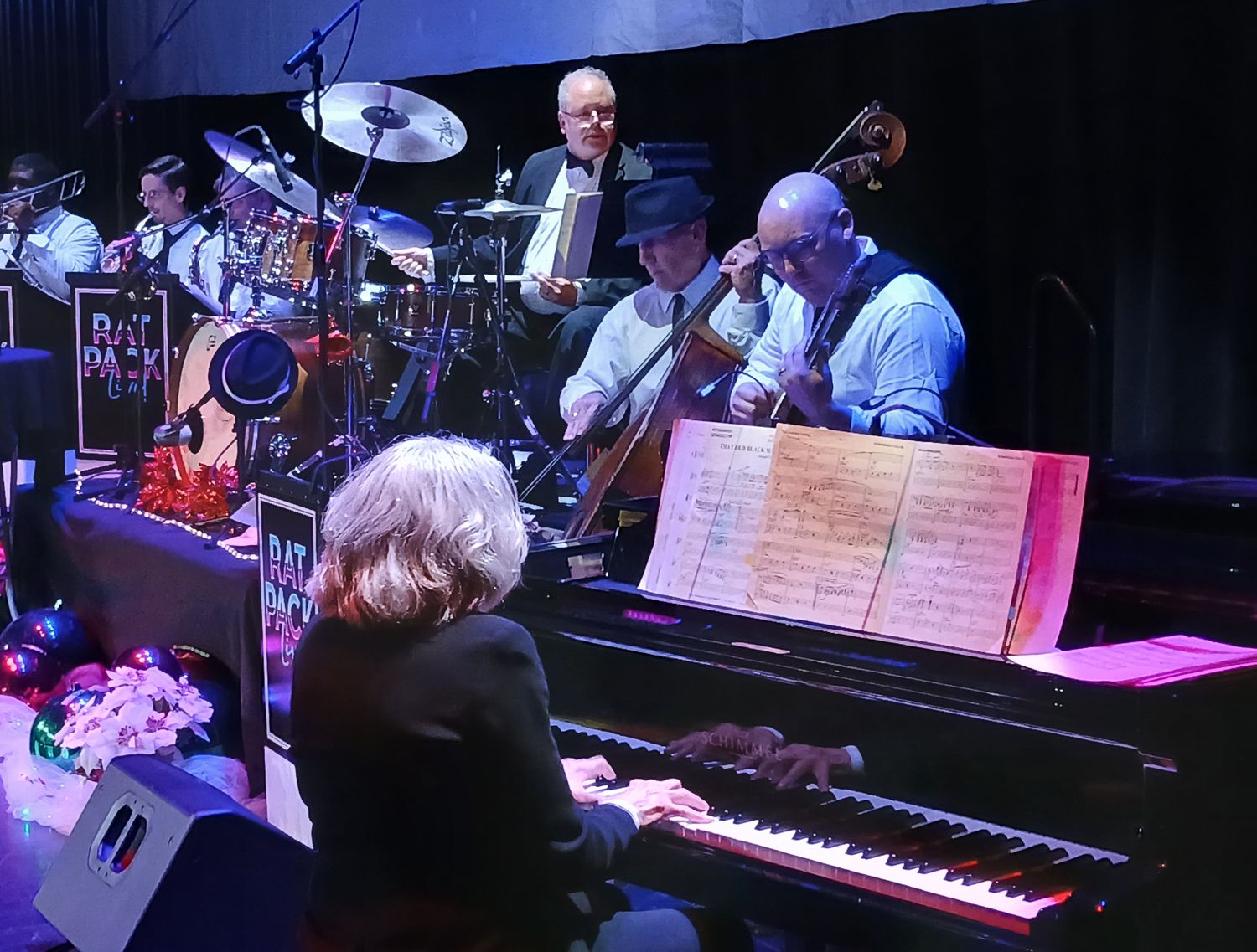 Becky Oexler at the grand piano with a jazz band behind her